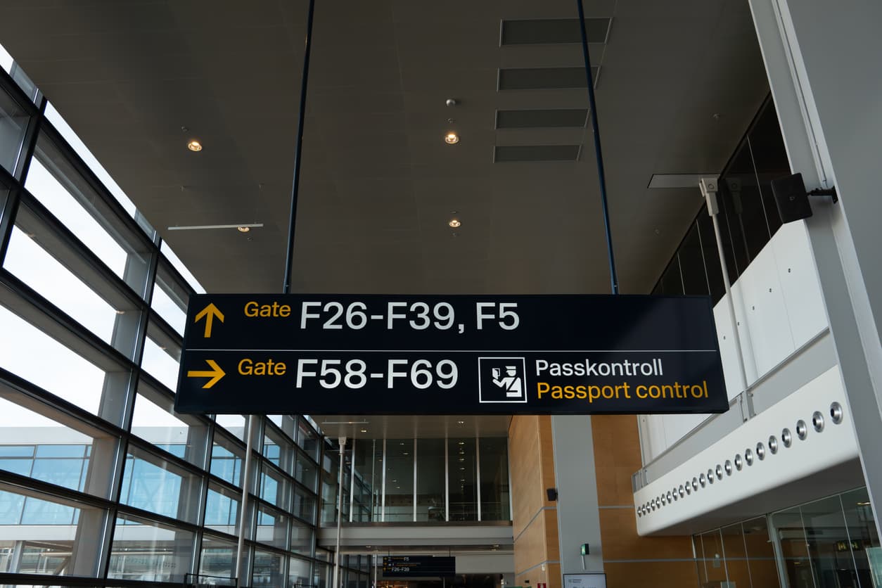 Skylt med vägvisning till passkontroll på flygplats – symboliserar vikten av giltig passkopia vid internationella resor och dokumenthantering.